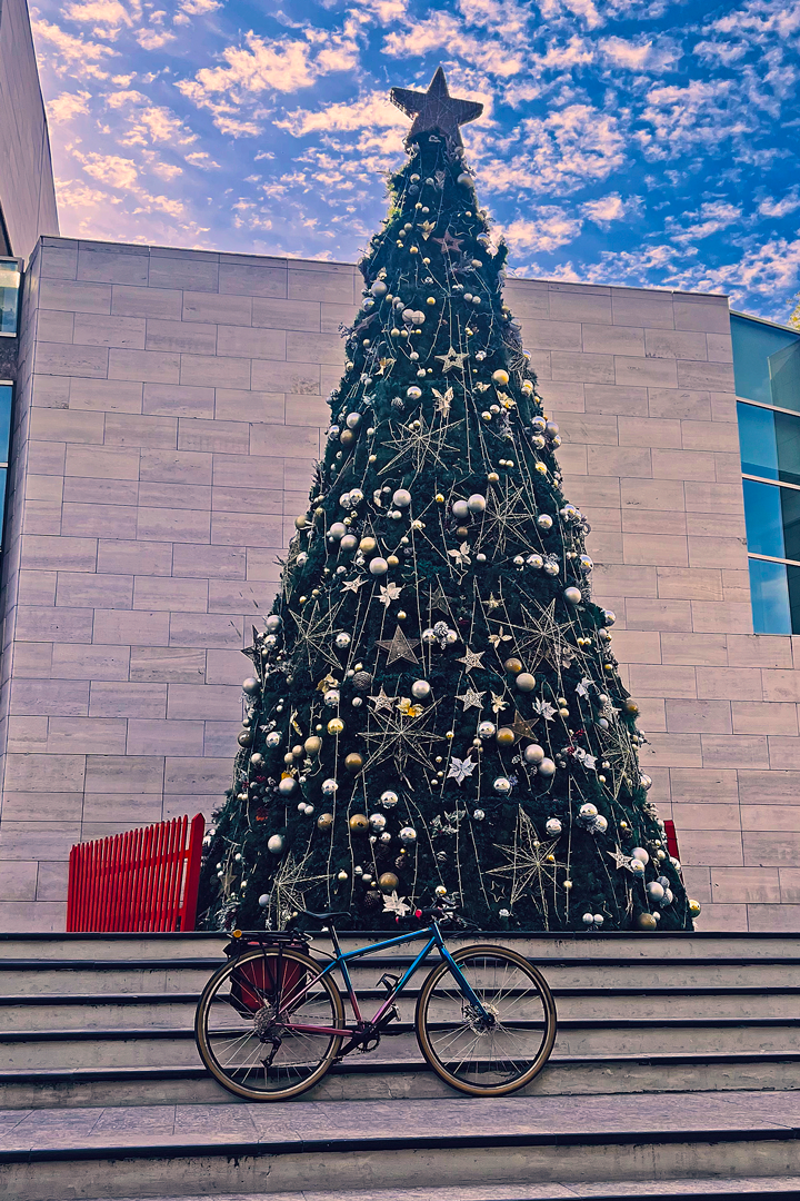 Árbol de Navidad decorado con adornos dorados y plateados en el frontis de la Municipalidad de Vitacura con una bicicleta híbrida ubicada al frente